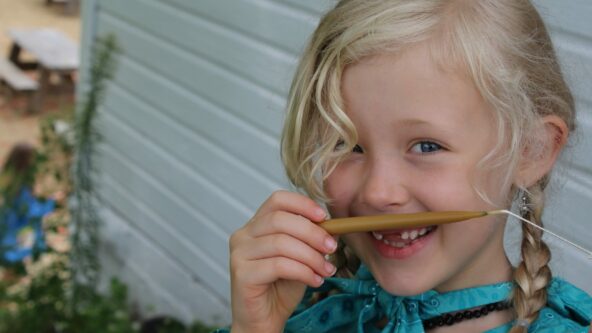 A child is smelling a beeswax candle.